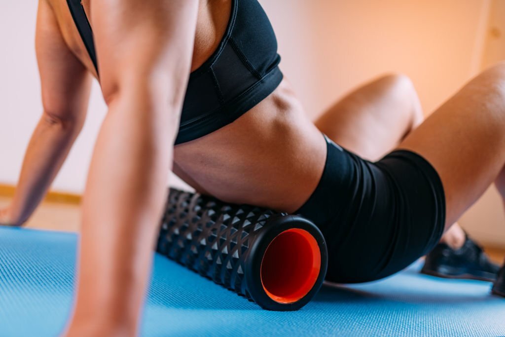 Woman Massaging Lower Back Muscles with Foam Roller at Home
